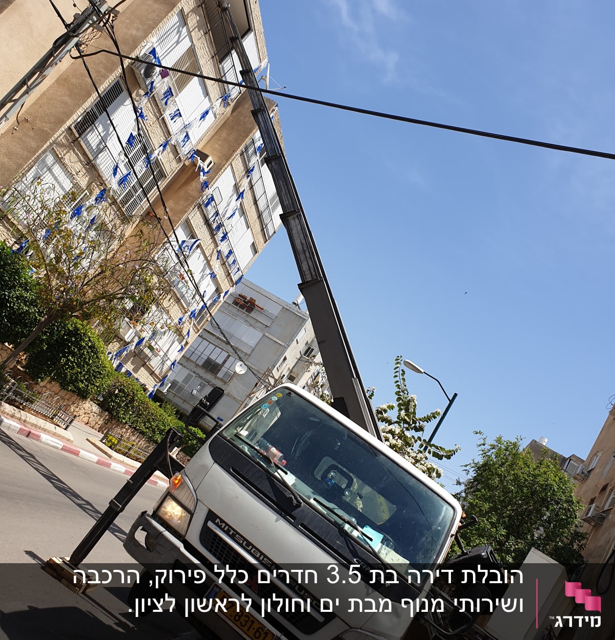 משאית עם מנוף חונה ברחוב ליד בניין